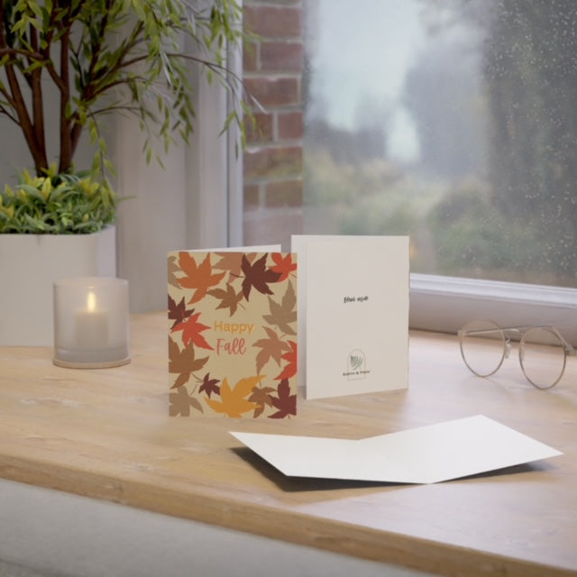 Mockup of fall greeting card displaying the front design with 'Happy Fall' and colorful falling leaves, blank inside, and company logo on the back