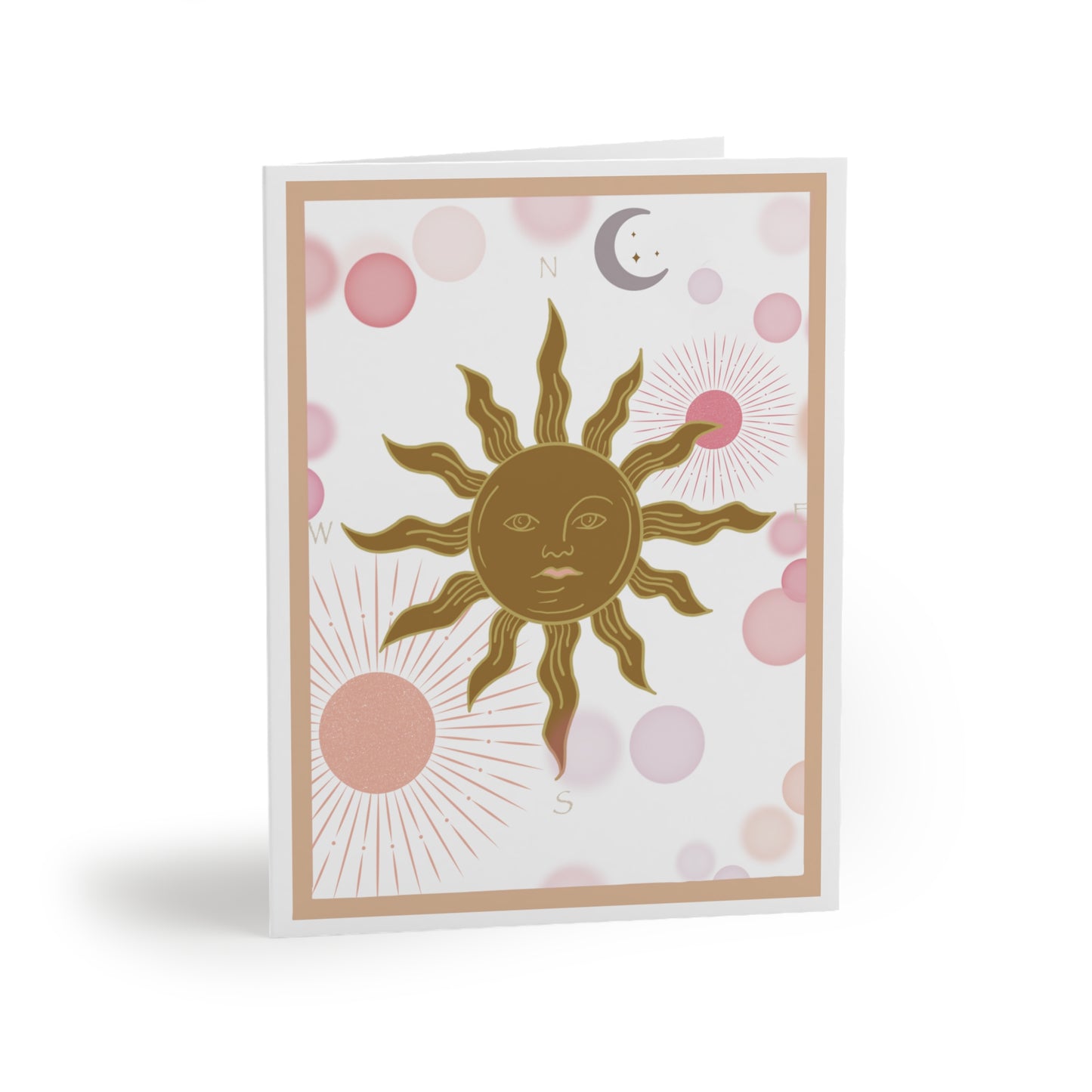 White greeting card with a light coral border. Inside the border is a golden sun with flame points. The sun is a compass with the North, South, East, west marked accordingly. Light Pink and coral planets torbit around in the background along with a lavender colored moon.