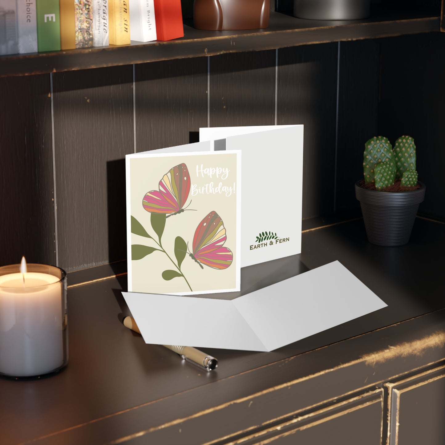 Mockup of birthday greeting card displaying the front design with two colorful butterflies and 'HAPPY BIRTHDAY,' blank inside, and company logo on the back