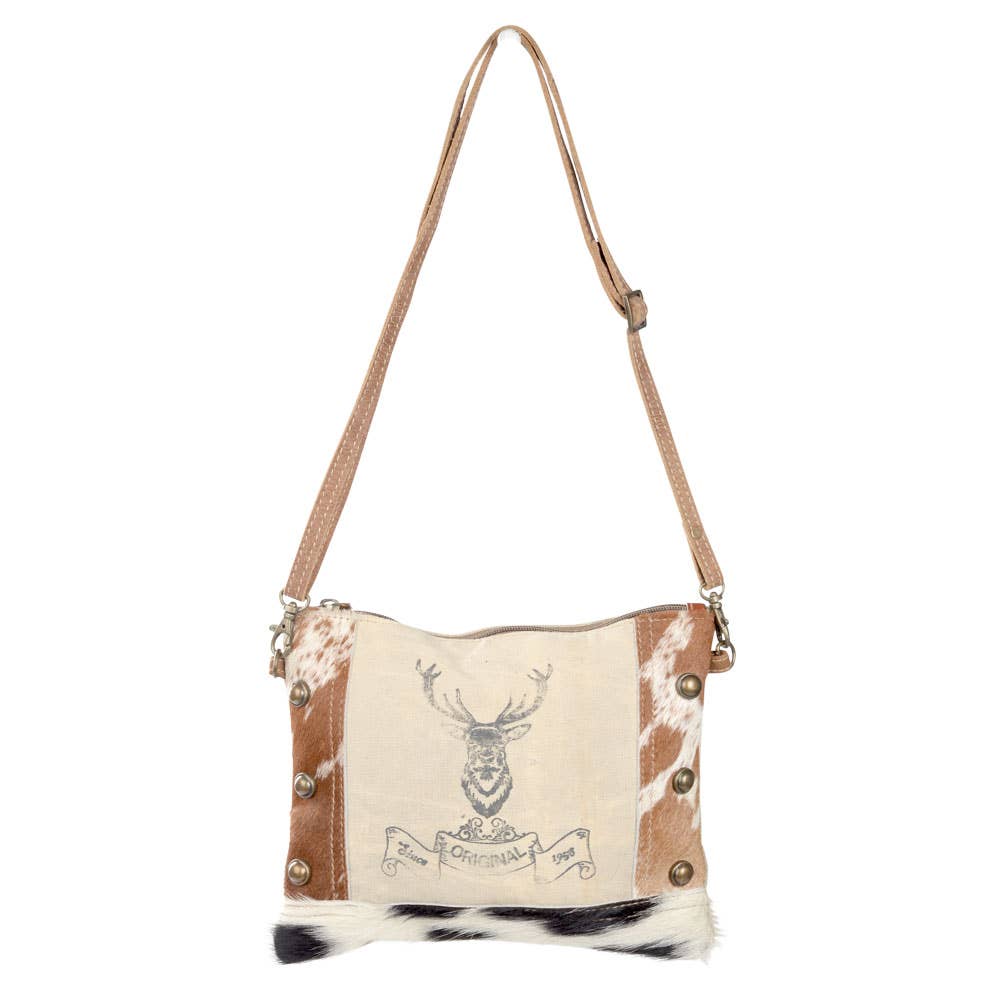 Eco-friendly crossbody bag with cowhide accents, tan and white on top80%, black and white on the bottom 20 %, crafted from repurposed military tent canvas, featuring a bold buck design on canvas on the front. Durable and stylish, perfect for outdoor enthusiasts and sustainable fashion lovers