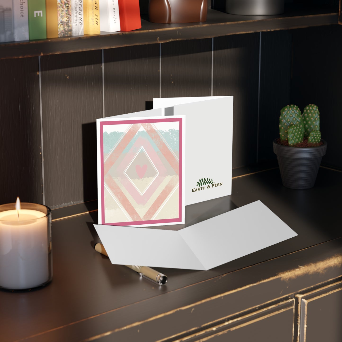 Mockup of southwest abstract diamond greeting card showcasing the front design with orange, pink, cream, and sky blue geometric patterns, blank inside, and company logo on the back.