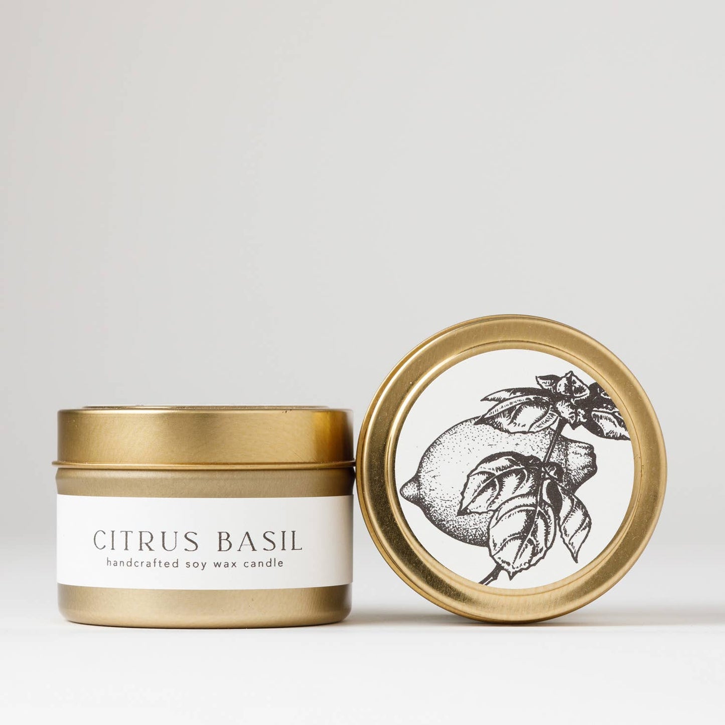 Hand-poured 4 oz. soy candle from the Flora Collection with citrus and herb scents of sweet basil, Meyer lemon, lime, and wild mint, in a gold steel travel tin.