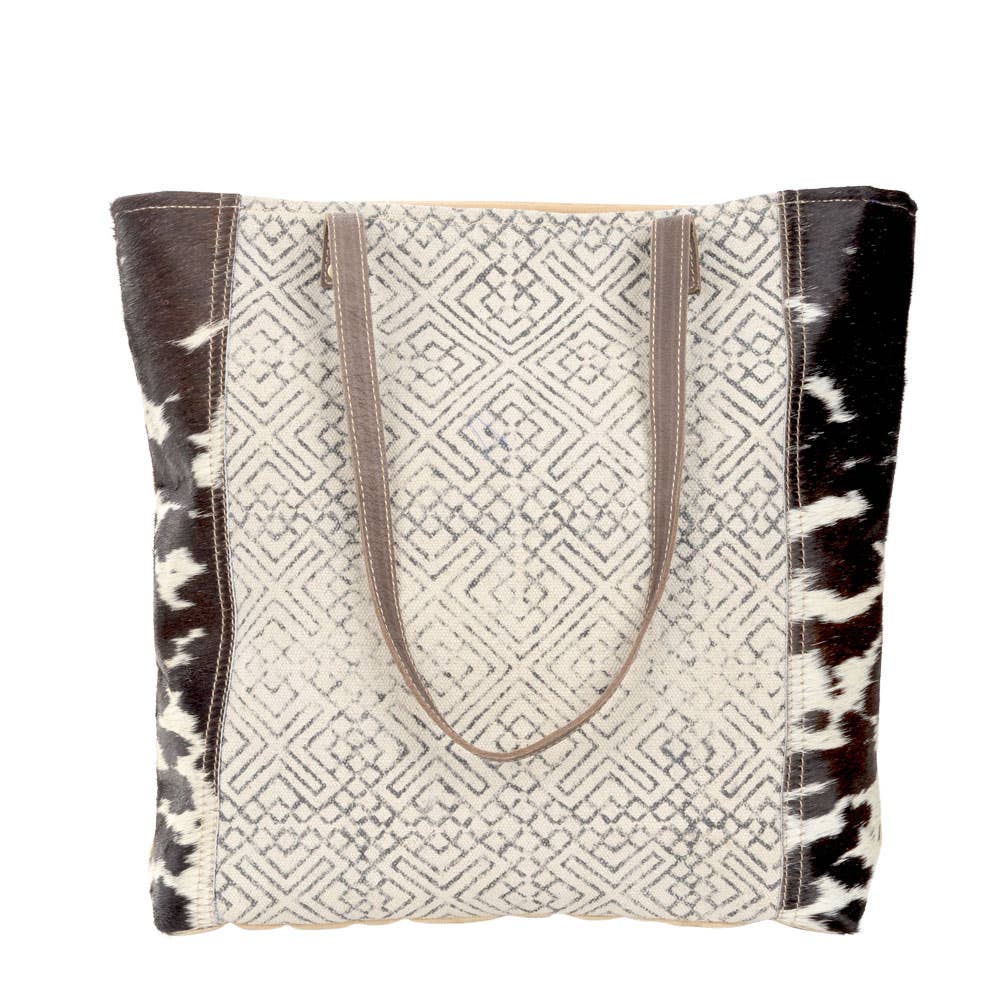 Black and cream geometric design tote with dark brown leather straps and cowhide accents. Stylish and eco-friendly, perfect for everyday use or as a statement accessory