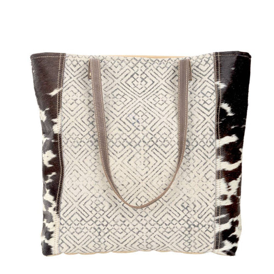 Black and cream geometric design tote with dark brown leather straps and cowhide accents. Stylish and eco-friendly, perfect for everyday use or as a statement accessory