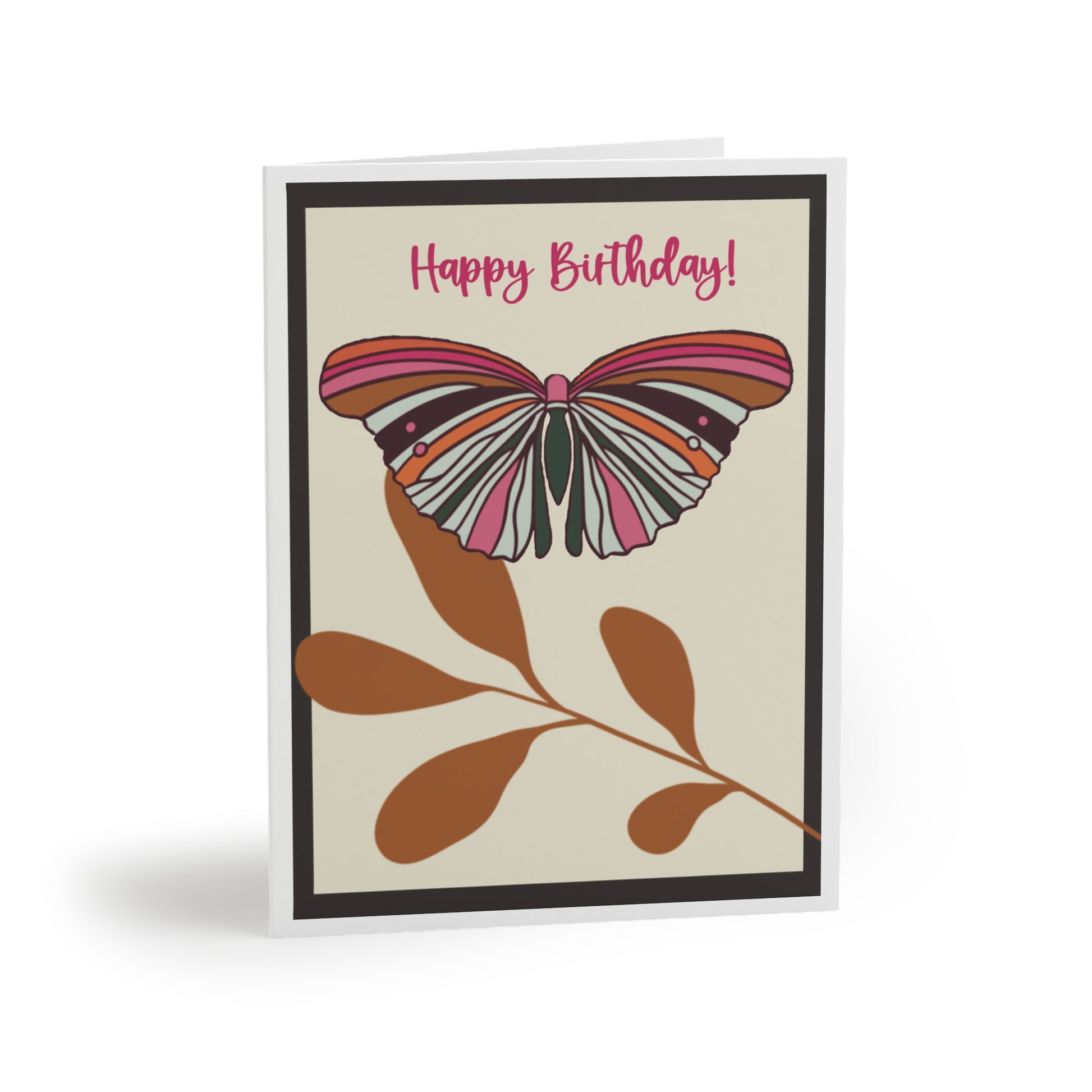 Greeting card featuring a cream background and black border, showcasing a colorful butterfly in pink, hot pink, orange, tan, and forest green perched on tan leaves
