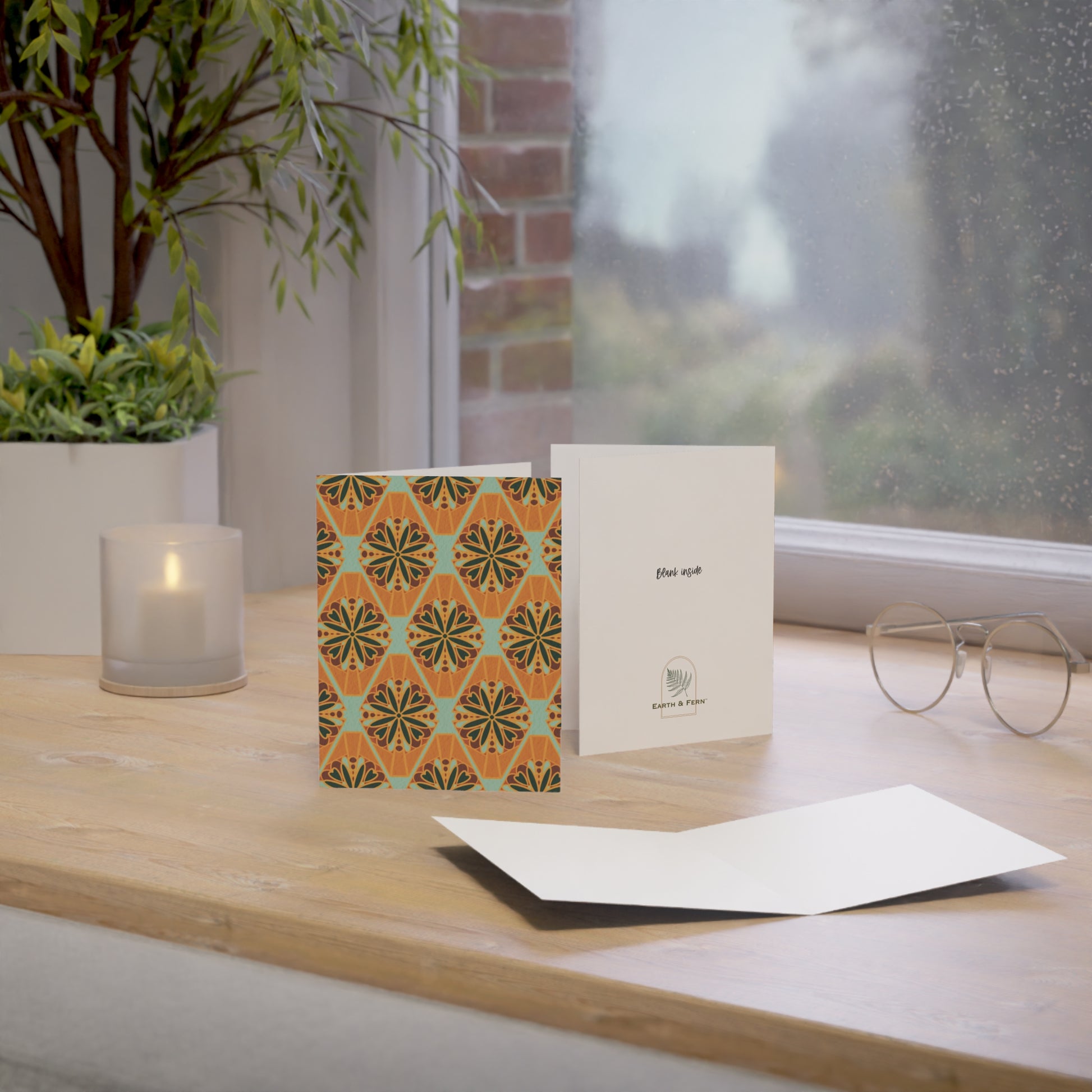 Front of a greeting card featuring a colorful millefiori design, showcasing a repeating pattern of vibrant flower tiles in various hues. Millefiori, an Italian term meaning 'a thousand flowers,' creates a stunning floral mosaic effect. The inside of the card is blank, perfect for personal messages, with the back featuring the text 'Blank inside' and the company logo. Ideal for sending floral greetings, birthday wishes, or any special occasion