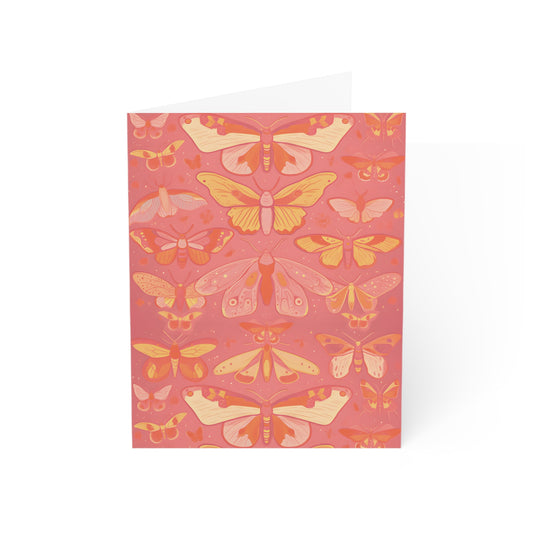 Image shows a greeting card with rows of butterflies in a collection. The butterflies are colored in shades of pink, yellow and orange. On a coral pink background with no border.
