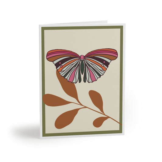 Image shows a Greeting Card with  a single colorful butterfly with the colors pink, orange, hot pink, cream and sits on a desert brown colored leaf.  The background is cream with a double border of sage green and white.
