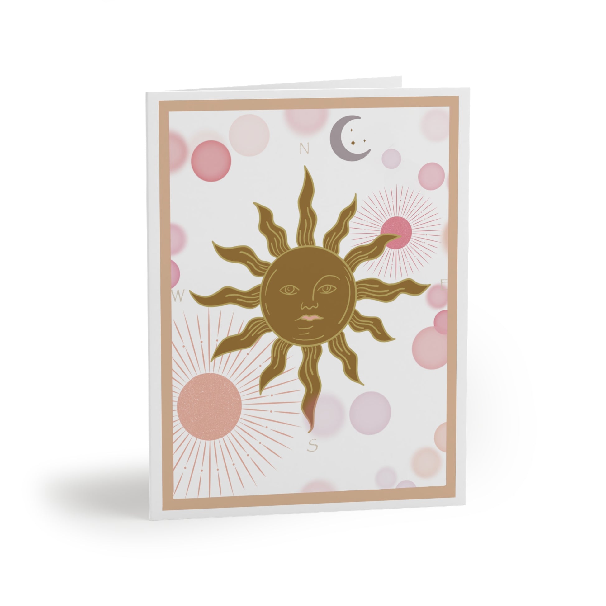 White greeting card with a light coral border. Inside the border is a golden sun with flame points. The sun is a compass with the North, South, East, west marked accordingly. Light Pink and coral planets torbit around in the background along with a lavender colored moon.