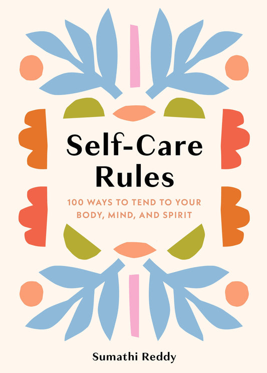 Cup of coffee, book titled 'Self-Care Rules', and lit candle on a wooden table with a bed in the background.