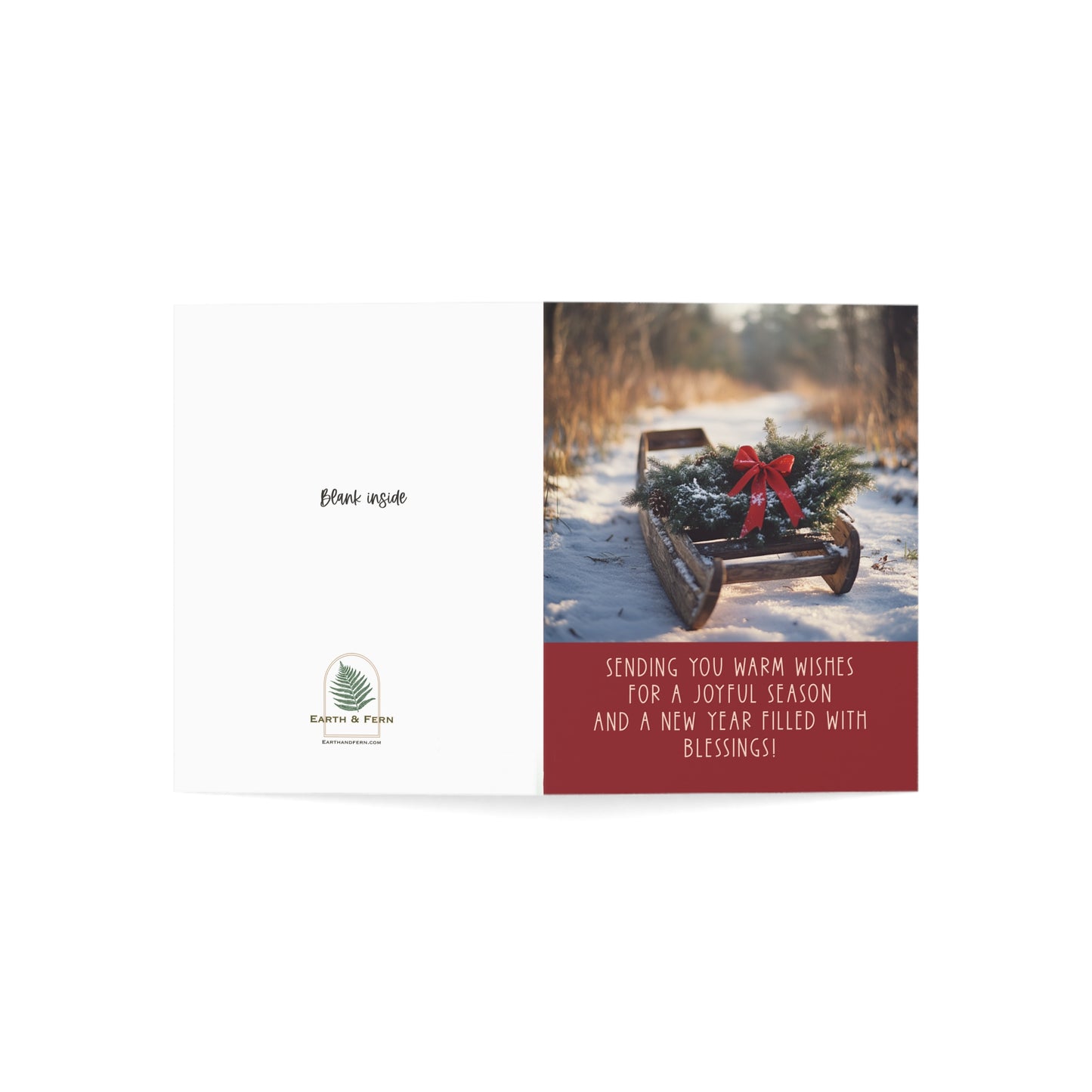 Mockup of holiday greeting card featuring a vintage wooden sled with an evergreen wreath and red bow on a snowy path. The front includes the message: 'Sending you warm wishes for a joyful season and a new year filled with blessings.' The inside is blank for a personalized message. The back features the Earth & Fern logo with the words 'Blank Inside