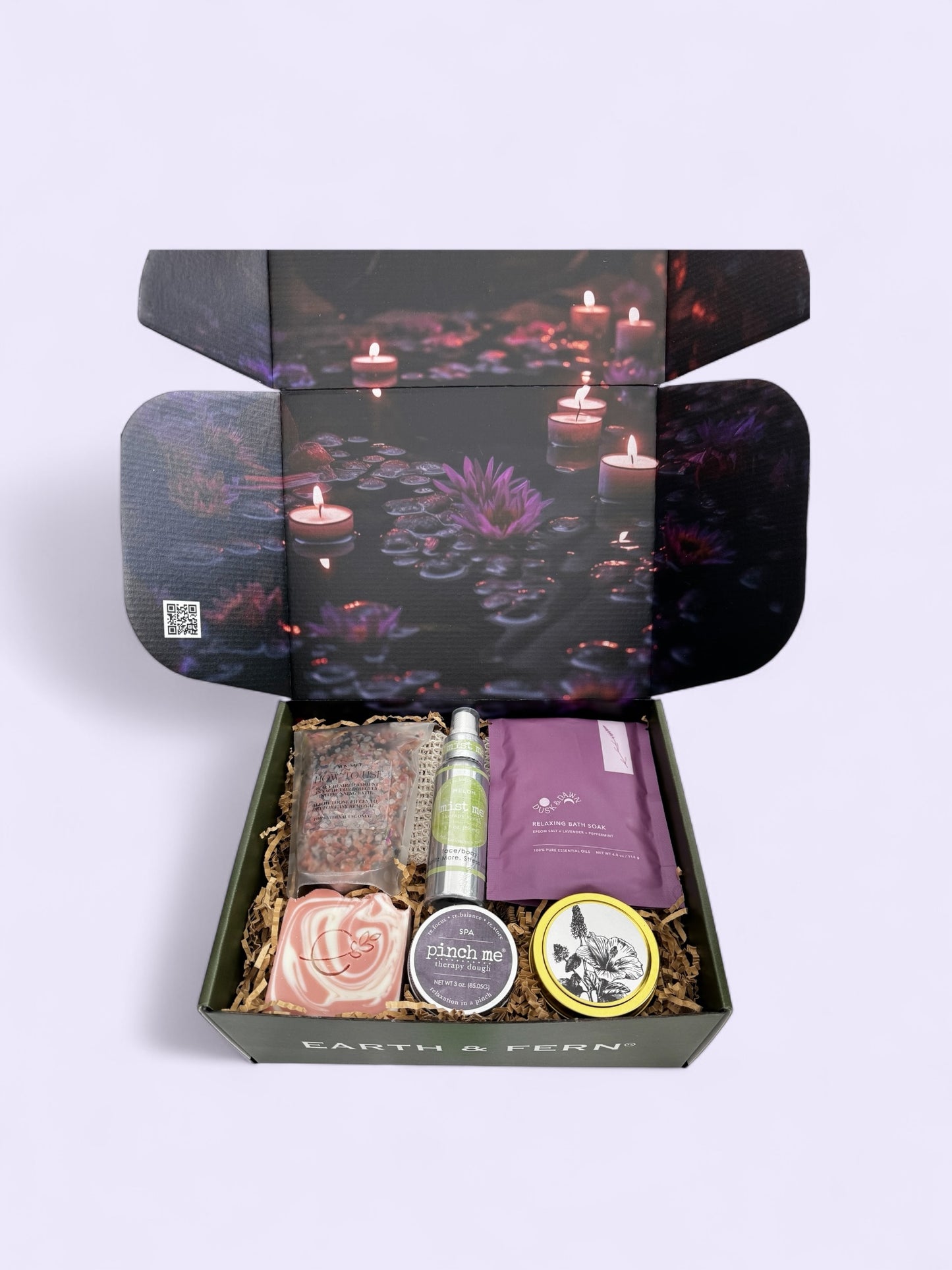Open box with Midnight Mood and Dusk to Dawn bath soaks, Aromatherapy Spray for on the go, Therapy dough in lavender, hibiscus patchouli candle, and luxurious lavender rose soap, with complimentary sisal soap bag.