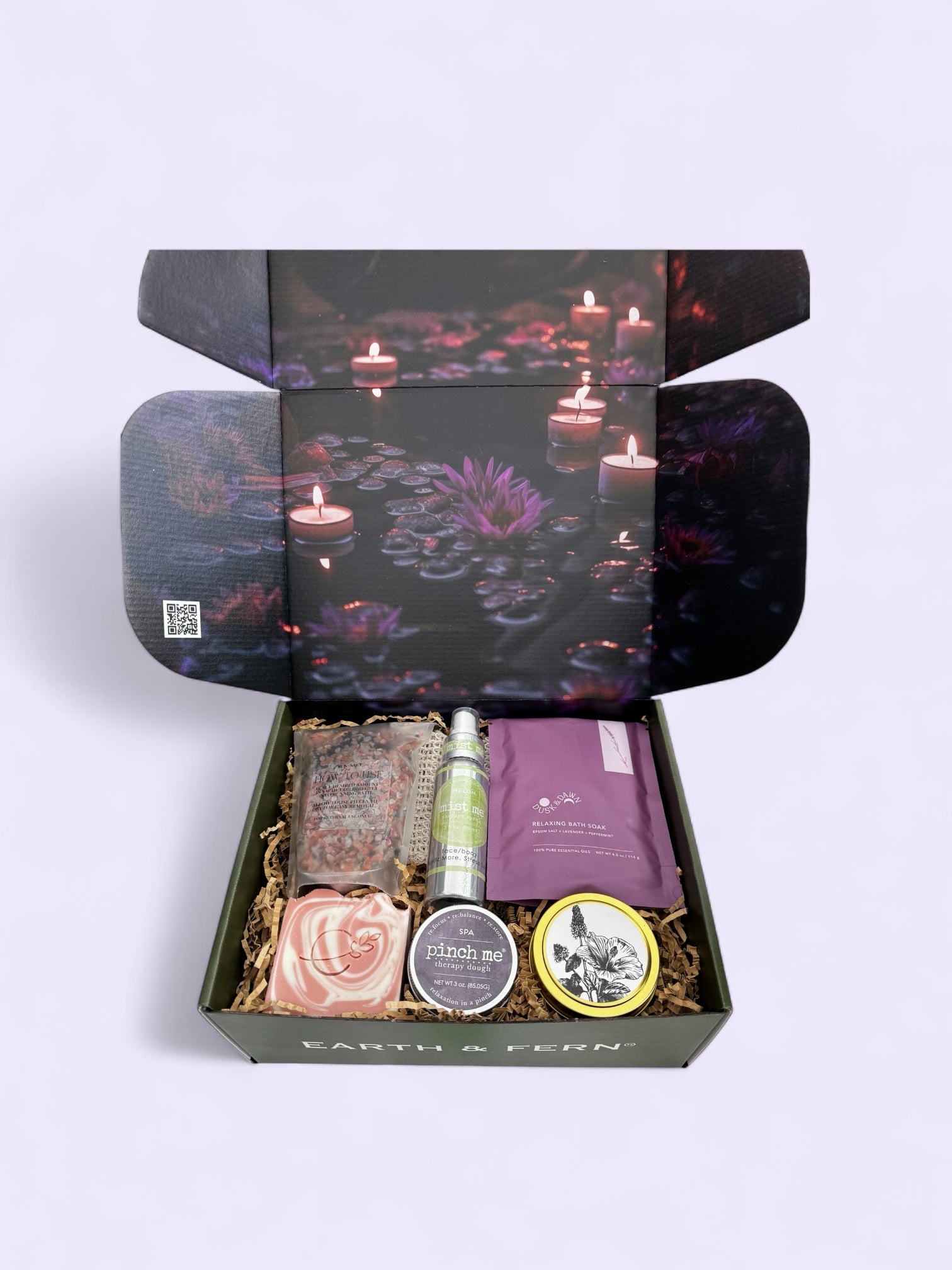 Open box with Midnight Mood and Dusk to Dawn bath soaks, Aromatherapy Spray for on the go, Therapy dough in lavender, hibiscus patchouli candle, and luxurious lavender rose soap, with complimentary sisal soap bag.