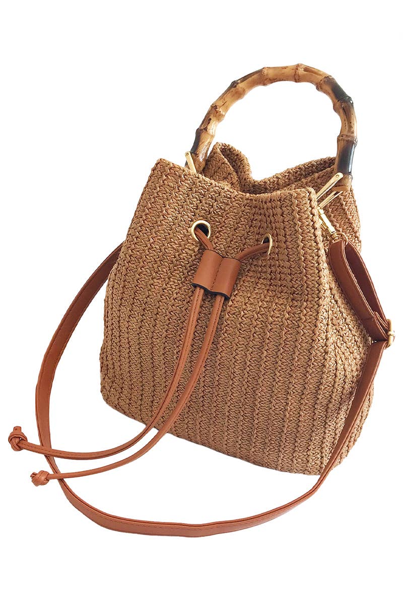 Boho-style woven rattan bucket bag with bamboo top handle and crossbody strap, featuring drawstring closure and inner compartments