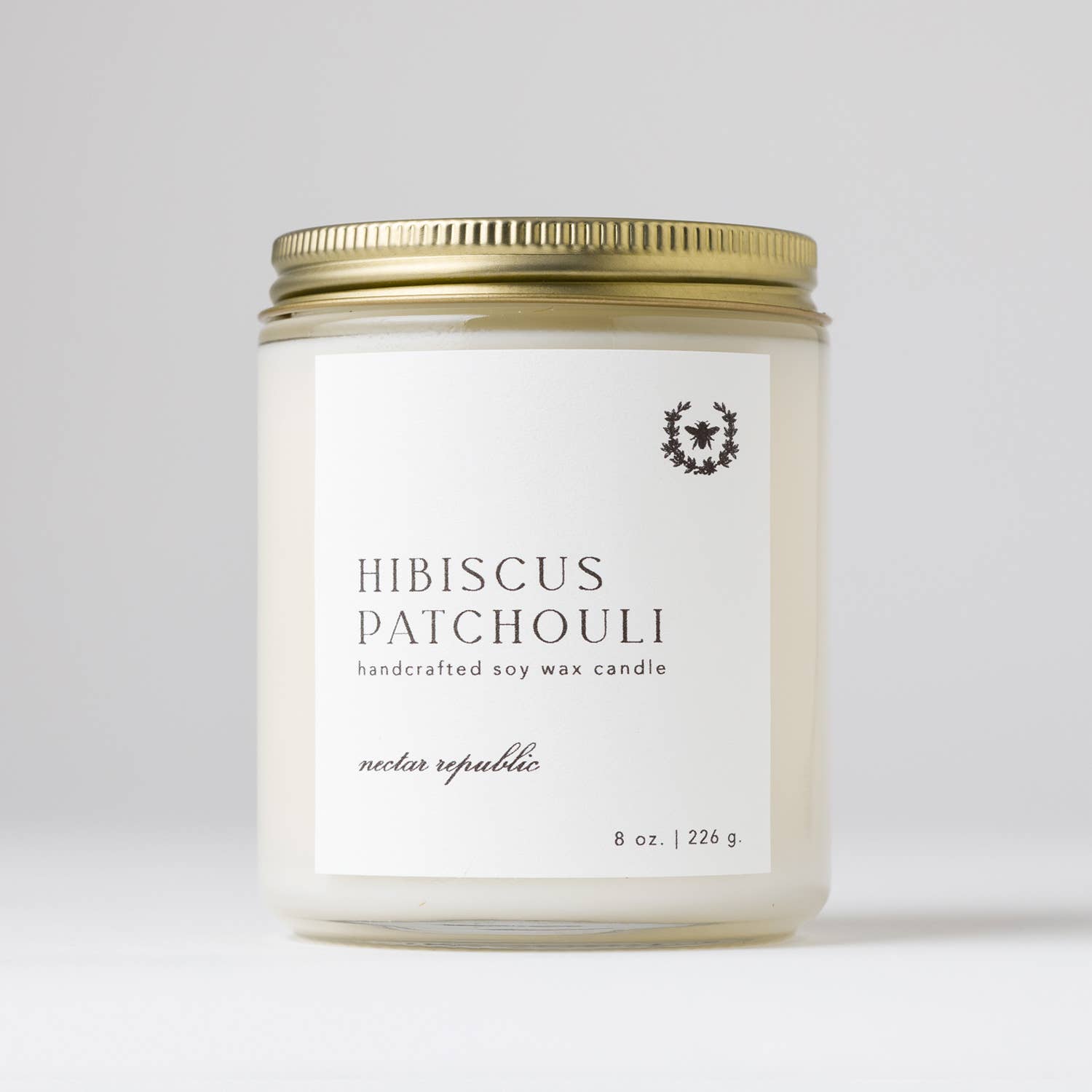 Hand-poured 8 oz. soy candle from the Flora Collection with floral island top notes and earthy patchouli, in a clear glass jar with a gold steel lid.